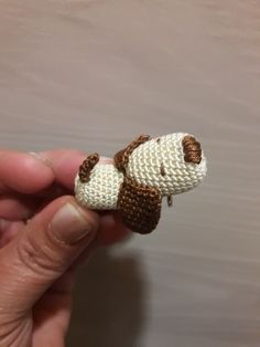 a hand holding a small crocheted stuffed animal in the shape of a dog