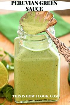 a glass jar filled with green sauce next to sliced limes