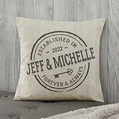 a personalized pillow on a couch in front of a wooden wall