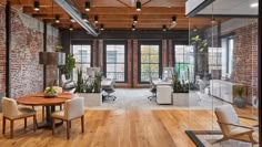 an office with exposed brick walls and wooden floors, along with white chairs and tables