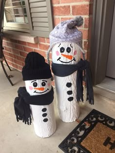 two snowmen made out of toilet paper rolls on the front porch, one wearing a hat and scarf