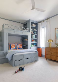 a bedroom with a bunk bed, bookshelf and drawers on the bottom floor