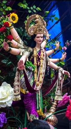 a statue of a woman with flowers in her hand and an elaborate headdress