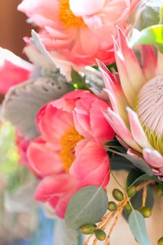 a vase filled with pink flowers and green leaves