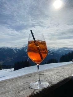 a drink sitting on top of a wooden table next to a snow covered mountain range