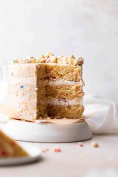 a cake with white frosting and sprinkles on it sitting on a plate