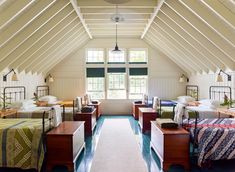 an attic bedroom with four beds and two nightstands on each side, in front of a large window