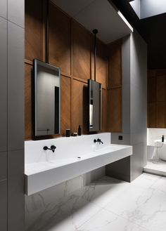 a bathroom with two sinks and mirrors in the wall above them is lit by recessed lights