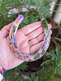 a person holding two different colored bracelets in their hand with flowers all over them