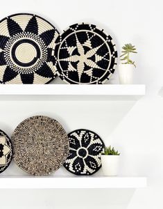 three white shelves with black and white plates on top of each shelf, one holding a potted plant