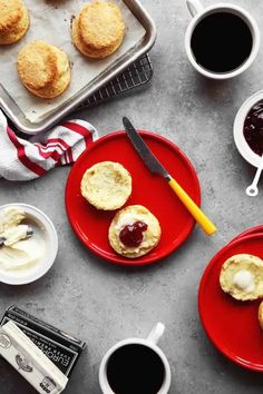 two red plates topped with cookies next to cups of coffee and muffin tins