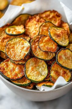 a white bowl filled with cooked zucchini on top of a marble countertop