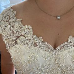 a woman wearing a wedding dress with pearls on the bottom and a diamond necklace attached to her neck