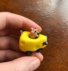 a small yellow toy car with a mouse in it's back sitting on a table