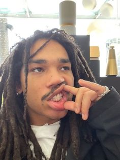 a man with dreadlocks and a fake moustache is making a funny face