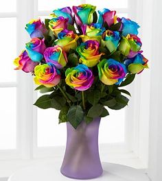 a vase filled with multicolored roses on top of a table