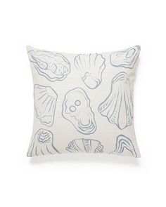 a blue and white pillow with seashells printed on it's front side