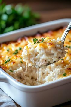 a spoonful of chicken and rice casserole being lifted with a fork from the casserole dish