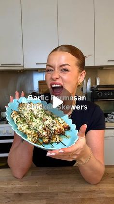 a woman holding a plate with food on it in front of her face and an open mouth