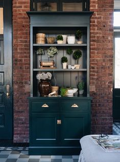 a green bookcase with potted plants on it in front of a black and white checkered floor