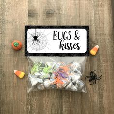 a bag filled with candy and halloween candies on top of a wooden table next to a sign that says, bugs & kisses