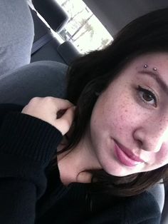 a woman with freckles on her face sitting in the back seat of a car