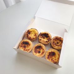 six small pizzas in a white box on a table