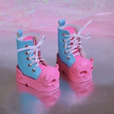 a pair of pink and blue high top shoes with pig ears on the soles