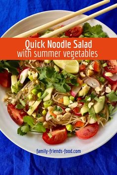 a white plate topped with salad and chopsticks next to blue table cloth covered in food