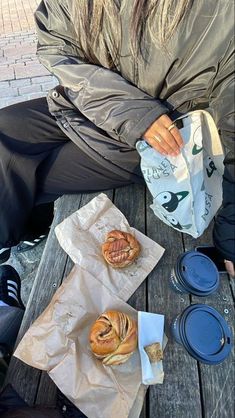 a woman sitting on a bench with some food in front of her and another bag