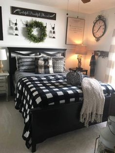 a bedroom with black and white bedding, wreaths on the wall and two lamps