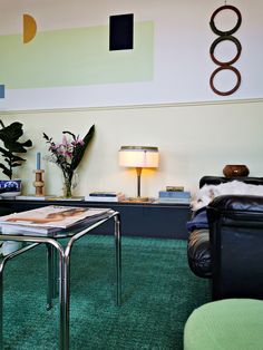 a living room filled with furniture and green carpeted flooring next to a wall