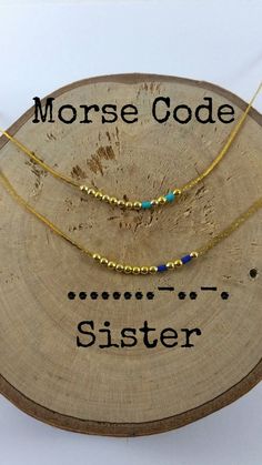 three gold necklaces with the words morse code and sister written on them in black ink