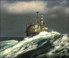 an oil rig in the middle of a large body of water under a cloudy sky