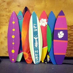 several surfboards are lined up against a wooden wall