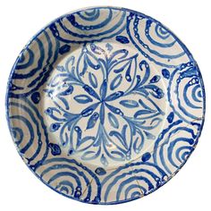 a blue and white plate with an intricate design on the rim, against a white background