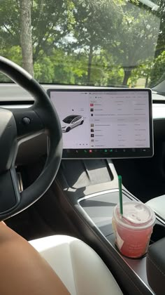 a car dashboard with a cup of coffee and a computer monitor on the dash board