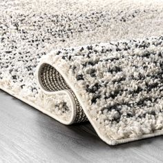 an area rug with black and white colors on the floor in front of a wooden table