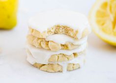 a stack of lemon cookies with icing and some sliced lemons in the background