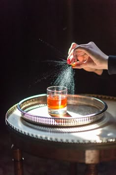 a person sprinkling sugar on top of a glass with a drink in it