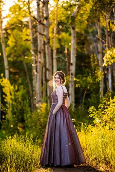 a woman in a purple dress standing in the woods