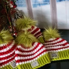 two hats with pom - poms are sitting on a window sill in front of a christmas tree