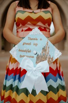 Sparkly blue graduation cap decorated with white flowers, the Disneyworld Castel, a white bow, and the quote: "there's a great big beautiful tomorrow" Theres A Great Big Beautiful Tomorrow Graduation Cap, Disney Castle Graduation Cap, Disney Theme Graduation Cap, Bridgerton Graduation Cap, Disney Inspired Graduation Caps, Disney Graduation Photos, High School Graduation Cap Designs Disney, Grad Cap Designs Disney, Disney Graduation Pictures