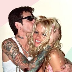 a man and woman kissing each other with tattoos on their arms