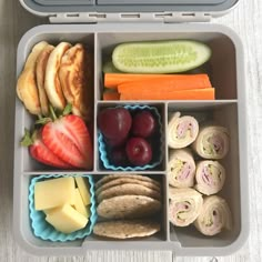 an open lunch box filled with fruit, crackers, and other food items on a table