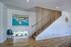 a living room filled with furniture and a wooden stair case next to a painting on the wall