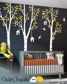 a baby's room with trees painted on the wall and a crib next to it