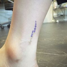 a woman's foot with a small flower tattoo on her left ankle and the word lavender written in purple ink