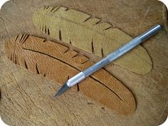 a pen sitting on top of a piece of wood next to a carving pattern with feathers