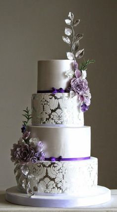 a three tiered wedding cake with purple and white flowers